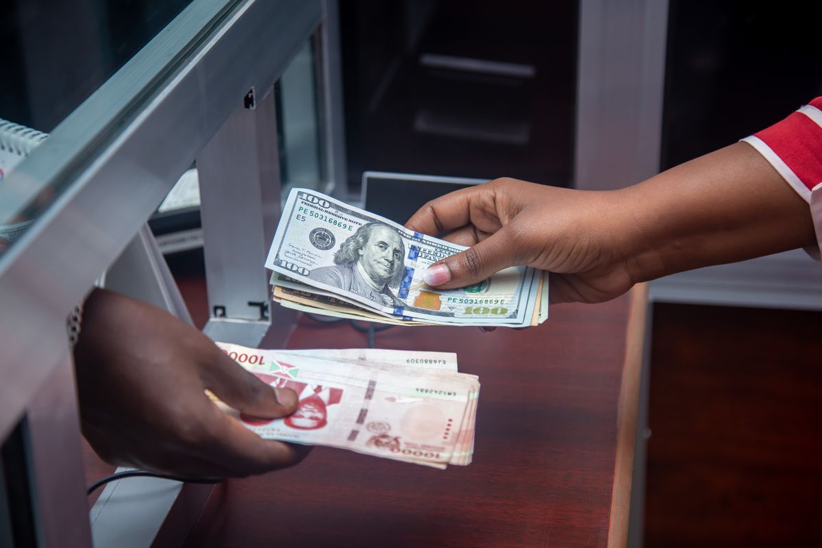 Dwie osoby wymieniają banknoty przez ladę w punkcie wymiany walut