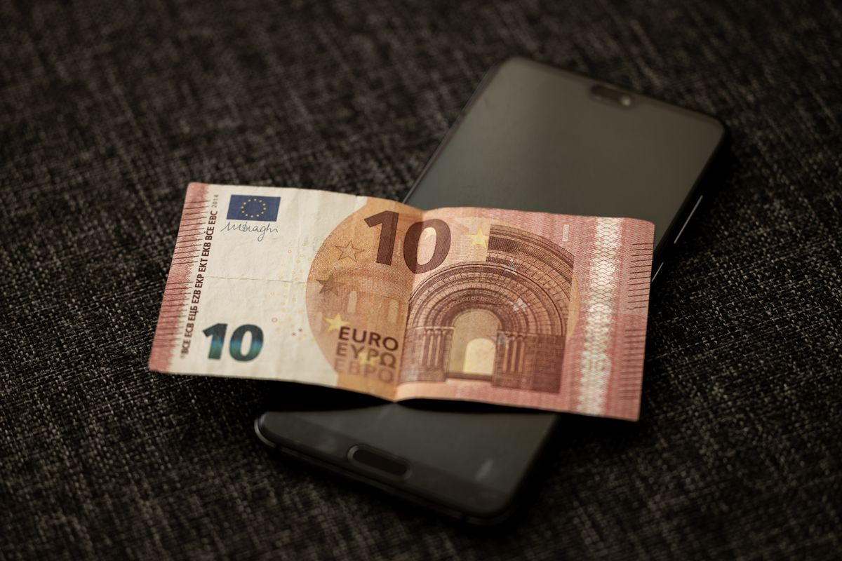 Banknot dziesięcioeurowy leżący na smartfonie